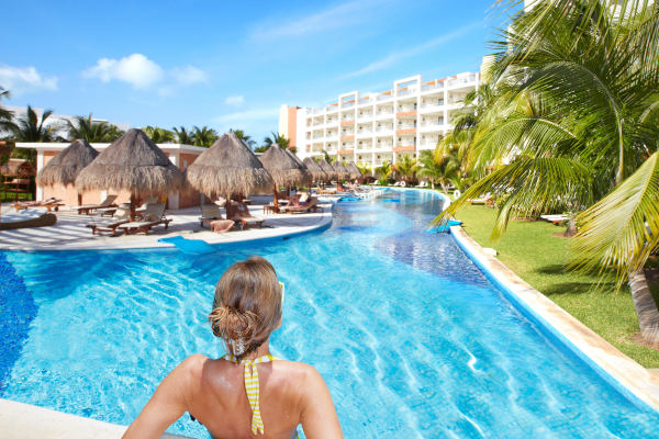 Turista femenina en el borde de una piscina de un complejo hotelero caribeño en un día soleado
