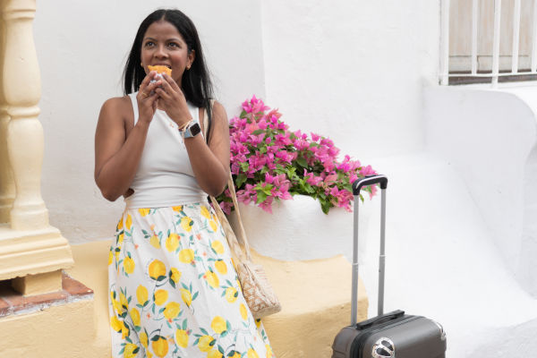 mujer viajera disfrutando una empanada colombiana.