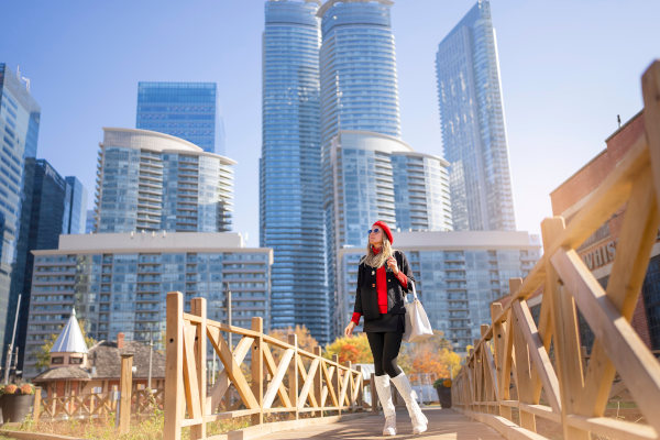 Mujer con bolso y boina mirando los rascacielos del centro de Toronto, Canadá