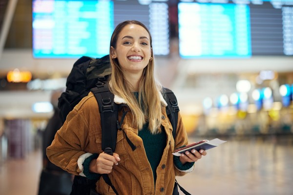 Mujer en aeropuerto con documentos de viaje en mano