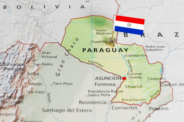 Mapa físico político de Paraguay con sus principales ciudades y una bandera nacional en miniatura.