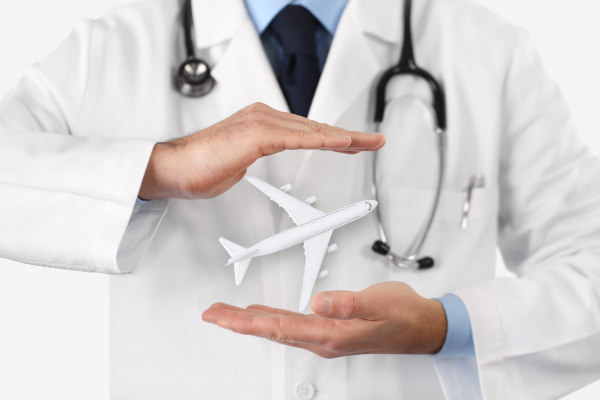 Médico sosteniendo entre las manos un avión en miniatura. Concepto de seguro médico de viaje.