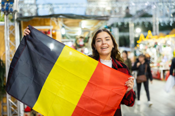 Joven viajera sonriente con la bandera de Bélgica.