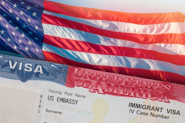 Visa americana sobre una bandera estadounidense, uno de los requisitos para viajar a Estados Unidos