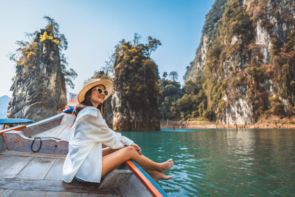 Mujer sentada en el borde de un bote típico tailandés en el Parque Nacional Khao Sok, Surat Thani, Tailandia.