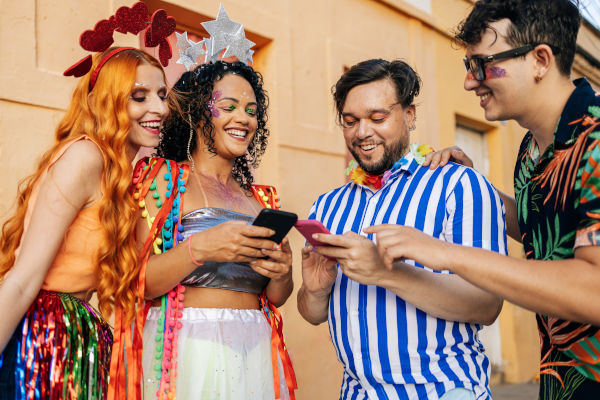 Grupo de amigos compartiendo imágenes con smartphones en una fiesta de Carnaval en Brasil.