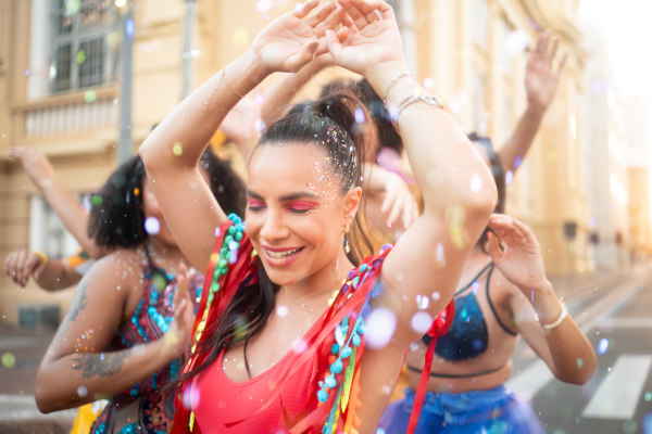 Mujeres con ropa y maquillaje colorido bailando en la calle en un carnaval en Brasil.