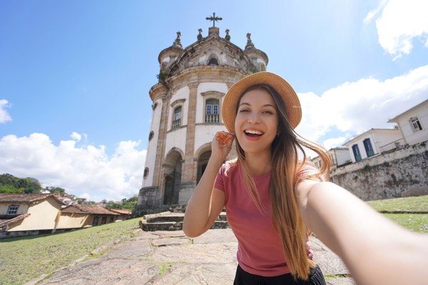 Chica tomándose una selfie con la iglesia de Nuestra Señora del Rosario en Ouro Preto, Minas Gerais, Brasil.