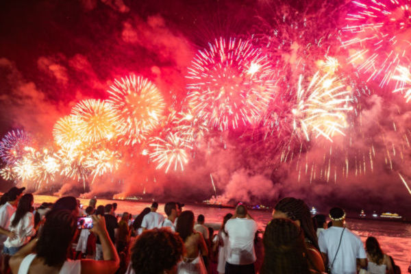 Multitud vestida de blanco observa los fuegos artificiales en la playa de Copacabana durante el Año Nuevo en Brasil.