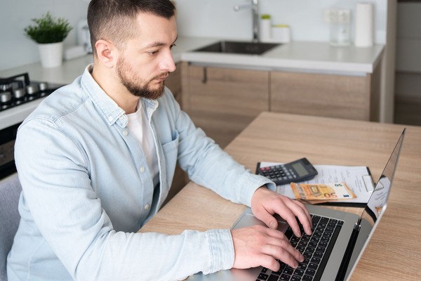 Hombre paraguayo que completa el formulario en su laptop y paga la tasa para tramitar el permiso ETIAS