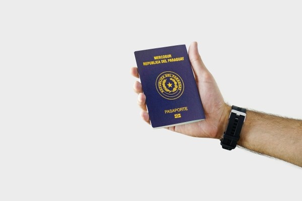 Persona sosteniendo un pasaporte paraguayo.