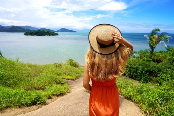 Mujer viajera con sombrero caminando por un sendero en Costa Verde, Río de Janeiro, Brasil.