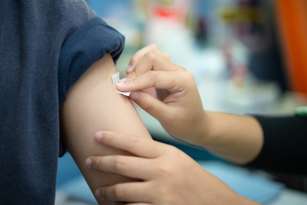 Primer plano de un médico preparando zona de vacunación en el brazo de un paciente.