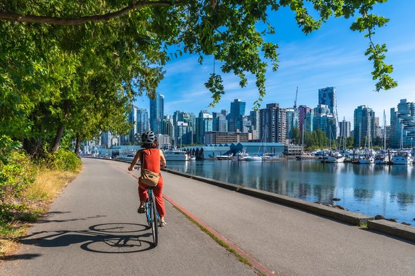Mujer en bicicleta en Stanley Park, disfrutando de las vistas de la ciudad de Vancouver, Canadá.