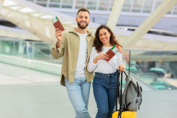 Smiling couple at an airport holding passports and travel documents, ready for their trip to Europe.