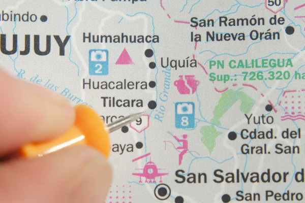 Persona con chincheta señalando Tilcara, en la provincia de Jujuy, en un mapa físico del norte argentino