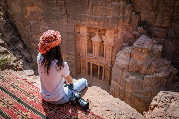 Mujer viajera sentada en el mirador de la alfombra en la ciudad de Petra, Jordania, mirando al Tesoro o Al-Khazneh.