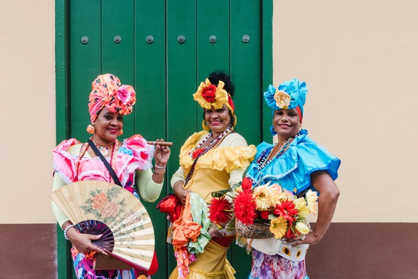 Tres mujeres afrocaribeñas con coloridos trajes tradicionales posando para la cámara en La Habana, Cuba